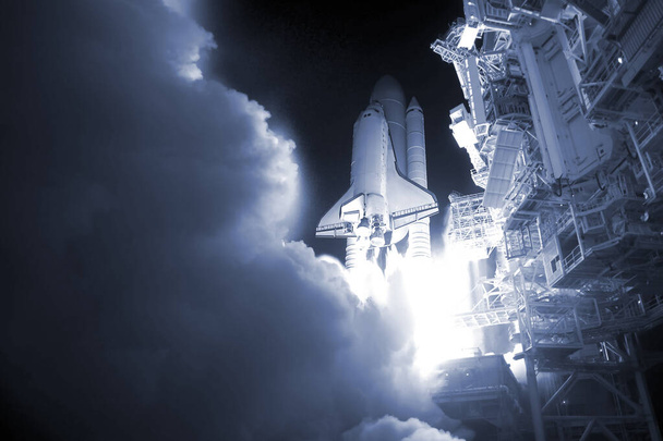 Запуск ракеты ночью, в облаках дыма. Элементы этого изображения были представлены НАСА
. - Фото, изображение