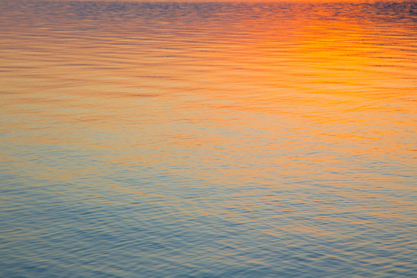 Clear water texture in blue and orange. Background of the ocean and the sea backlit by the sun. Soft waves. Natural water - Foto, imagen