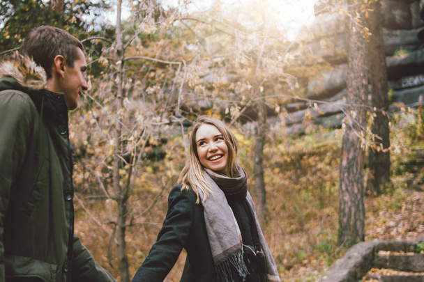 Ευτυχισμένο νεαρό ζευγάρι ερωτευμένων φίλων ντυμένοι με περιστασιακό στυλ περπατώντας μαζί στο δάσος του πάρκου της φύσης στην κρύα εποχή, οικογενειακά ταξίδια περιπέτειας - Φωτογραφία, εικόνα