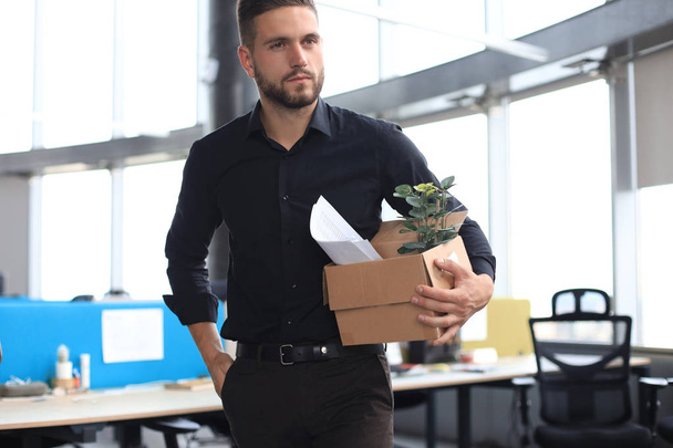 Sad dismissed worker is taking his office supplies with him from office - Foto, Bild