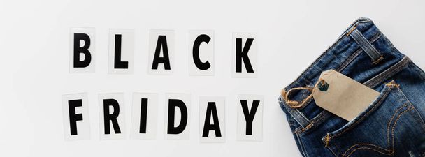 Creative promotion composition Black friday text and jeans on white background. Flat lay, top view, overhead, mockup, template. Minimal abstract background. Online shopping, sale, promo. Web banner - Fotoğraf, Görsel