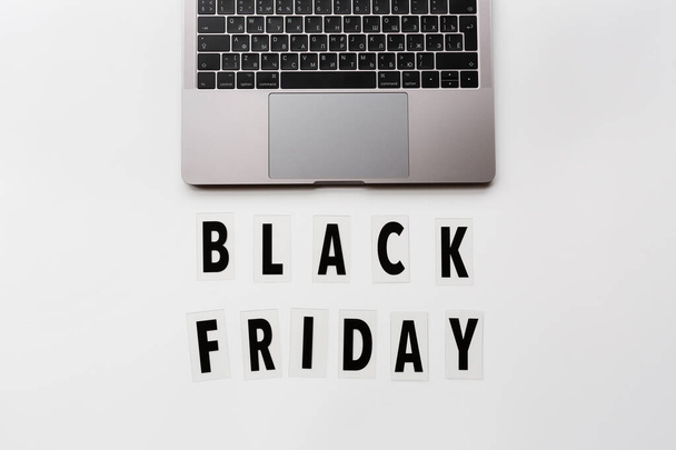 Creative promotion composition Black friday text and laptop on white background. Flat lay, top view, overhead, mockup, template. Minimal abstract background. Online shopping, sale, promo. Web banner - Photo, Image