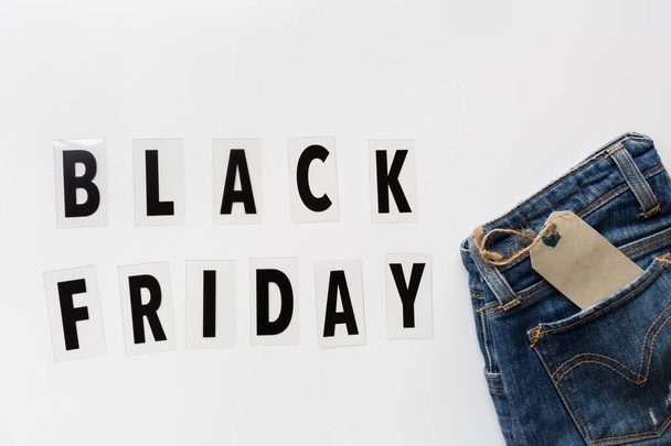 Creative promotion composition Black friday text and jeans on white background. Flat lay, top view, overhead, mockup, template. Minimal abstract background. Online shopping, sale, promo. Web banner - Foto, imagen