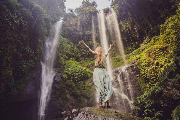 Woman in turquoise dress at the Sekumpul waterfalls in jungles on Bali island, Indonesia. Bali Travel Concept - Fotoğraf, Görsel