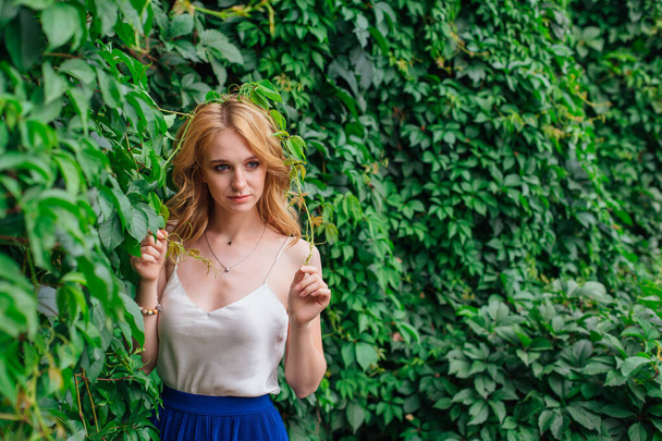 Portrait of a young beautiful woman, standing next to the wall of wild grape leaves. - Fotografie, Obrázek
