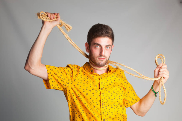 молодий хлопчик з мотузкою навколо шиї, відчайдушно грає, щоб забрати своє життя, щоб повісити себе, самогубство
 - Фото, зображення