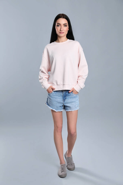 Full length portrait of young woman in sweater on grey background. Mock up for design - 写真・画像
