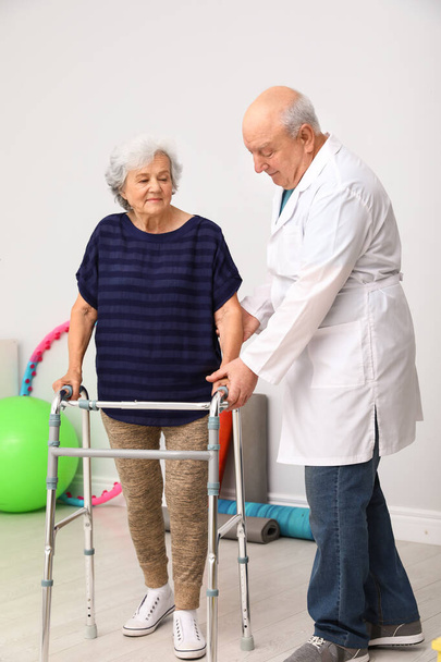 Dokter helpt oudere vrouw met het lopen frame binnen - Foto, afbeelding