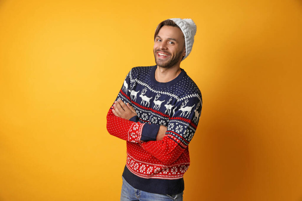 Young man in Christmas sweater and hat on yellow background - Fotoğraf, Görsel