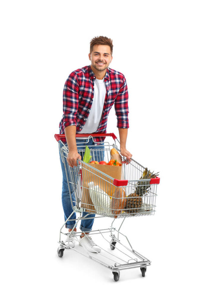 Young man with full shopping cart on white background - Foto, Bild