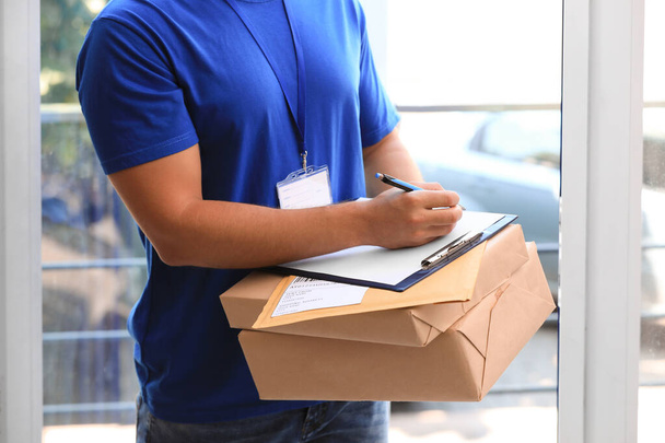 Young courier delivering parcels on doorstep, closeup - Foto, Imagem