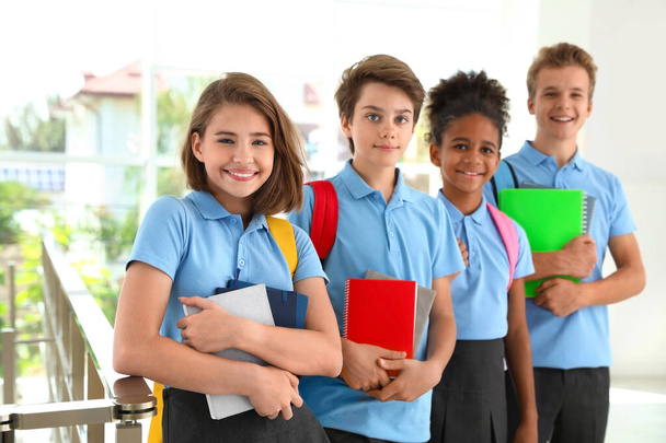 Happy pupils in school uniform with backpacks indoors - Foto, afbeelding