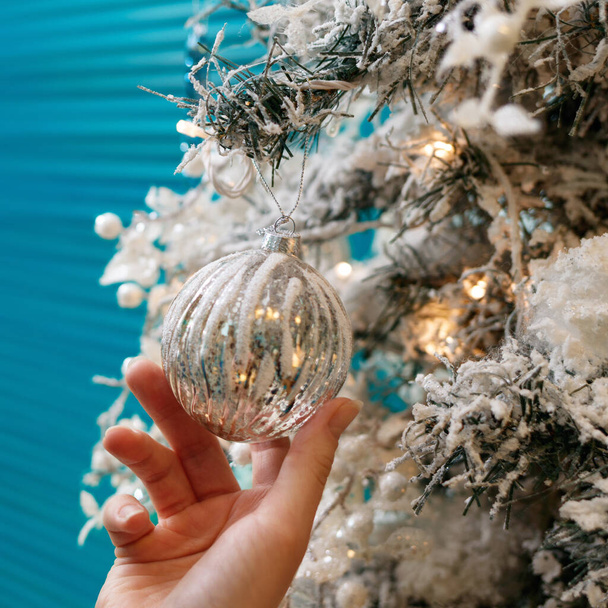 Hands decorating christmas tree with a silver balls. - Valokuva, kuva