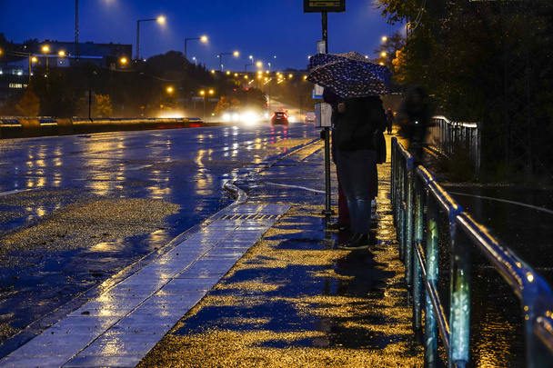 Sztokholm, Szwecja Pieszy z parasolem w deszczu na przystanku autobusowym. - Zdjęcie, obraz
