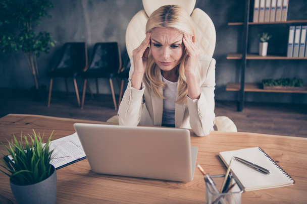 Photo of tired exhausted woman working as journalist for corporation staring into laptop sitting at desktop suffering from head ache pain hurt - 写真・画像