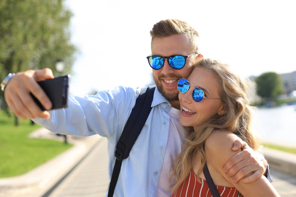 Loving cheerful happy couple taking selfie in the city - Fotó, kép
