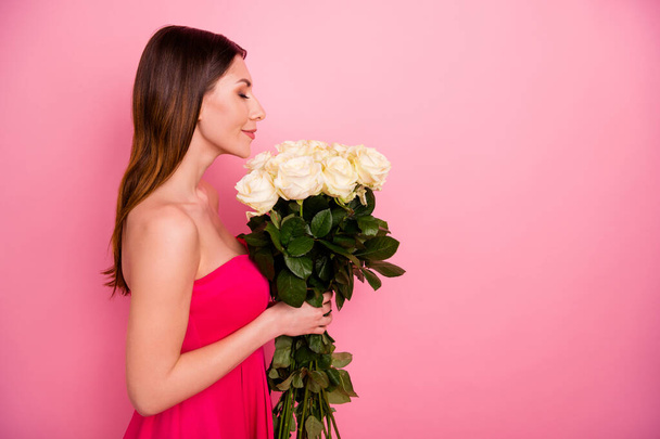 Profile side view portrait of her she nice attractive lovable lovely charming cute feminine delicate sweet calm peaceful girl holding in hands smelling roses isolated over pink pastel color background - Foto, Bild