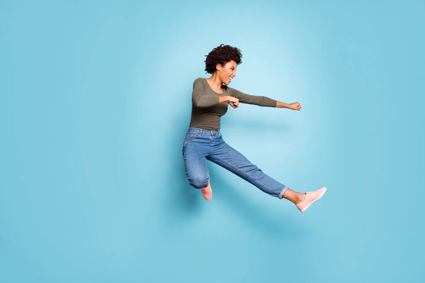 Full length photo of dark skin wavy lady jumping high dancing modern youngster moves practicing judo fighting wear casual outfit isolated pastel blue color background - Φωτογραφία, εικόνα