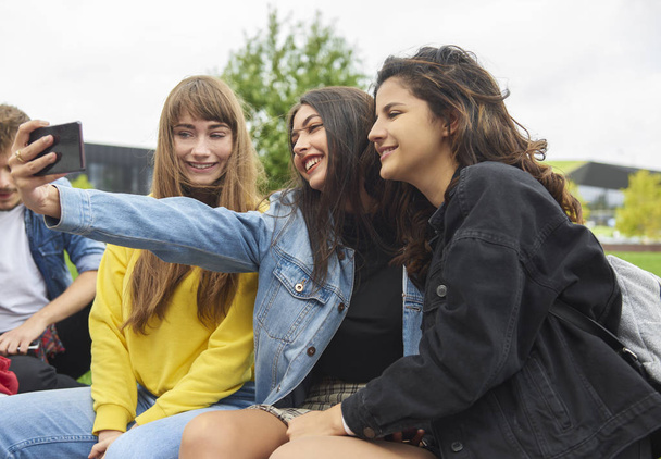 Three girls with mobile phone making a selfie - Photo, Image