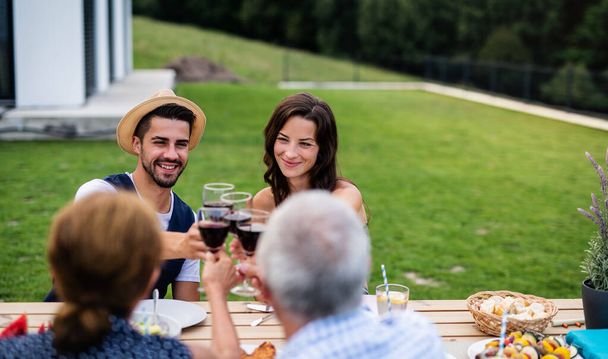 Portrait of people with wine outdoors on family garden barbecue. - Foto, immagini