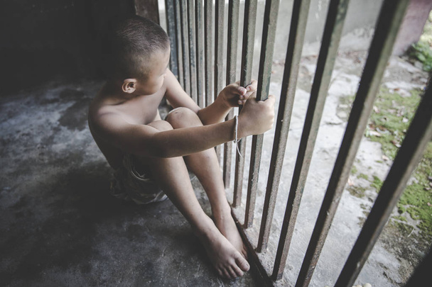  Kind umarmte sein Knie auf dem Boden, während es allein im Käfig saß - Foto, Bild