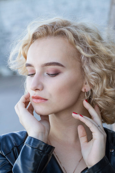 Porträt einer jungen Blondine mit hellem Make-up auf einem Granitwandhintergrund - Foto, Bild