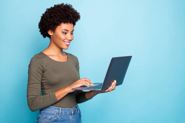 Portrait of positive cool confident afro american girl freelancer use laptop type emails chat with her partners business clients wear green style clothes denim jeans isolated blue color background - Foto, imagen
