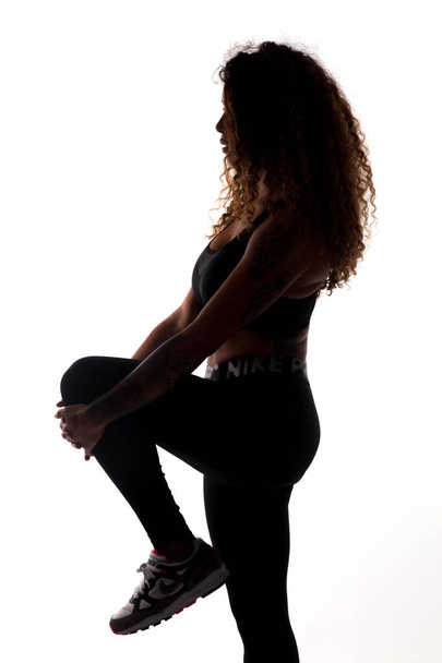 Девушка делает упражнения и гимнастические доски, личный тренер, черный силуэт на белом фоне женского профиля, хорошо подготовленное, идеальное тело
 - Фото, изображение