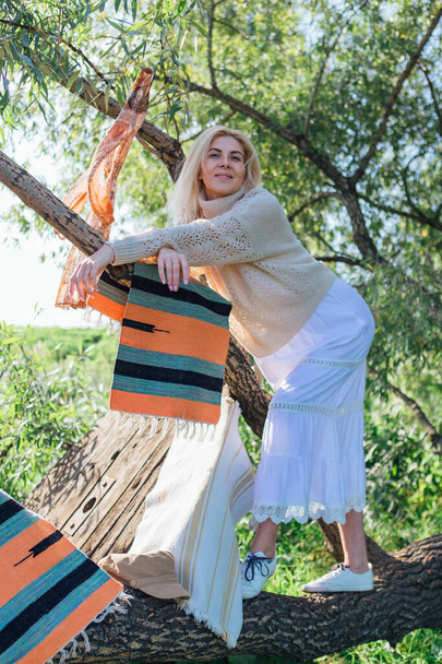 Happy beautiful blond woman standing on the big tree brunch - Foto, afbeelding