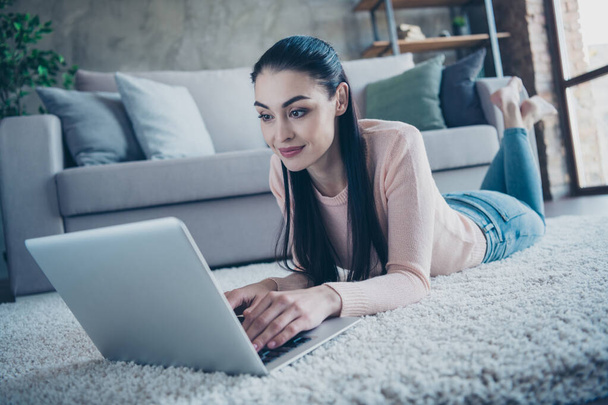 Close up photo of pretty lady chatting with friends over notebook reading new email letter lying comfy on floor wearing pullover and jeans in apartment - Photo, Image