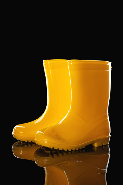 Μπότες κίτρινο καουτσούκ βροχή για τα παιδιά που απομονώνονται σε μαύρο φόντο - Φωτογραφία, εικόνα