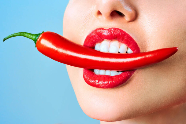 Mooie vrouw tanden eten rode Hot Chili peper tandheelkundige kliniek patiënt. Afbeelding symboliseert mondverzorging tandheelkunde, stomatologie. - Foto, afbeelding