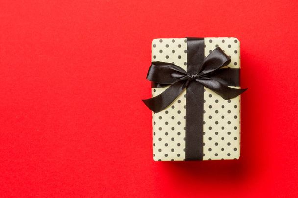 Top vue boîte cadeau de Noël avec arc noir sur fond rouge avec espace de copie - Photo, image