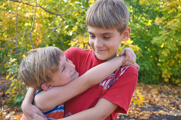 The younger brother hugs the older one and looks at him, two lov - Photo, Image