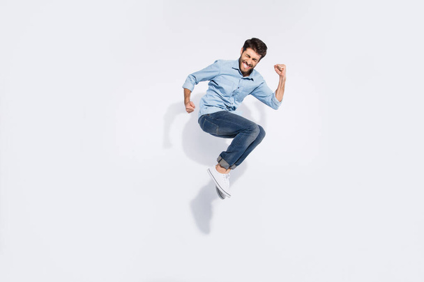 Full body profile photo of funny arabian guy jumping high rejoicing of great win raising fists wear casual denim shirt isolated white color background - Foto, Bild