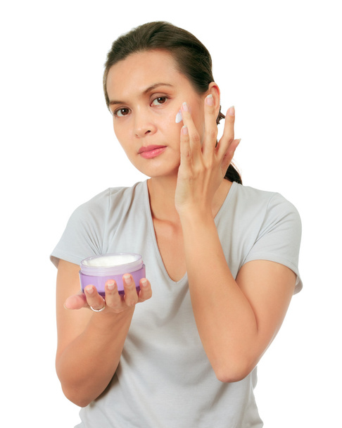 Isolated Middle Age Asian Woman apllies cream on her face. - Photo, Image