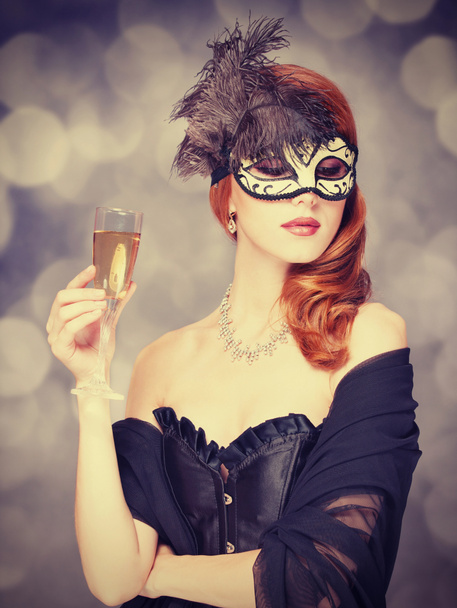roodharige vrouwen in masker met champagne - Foto, afbeelding