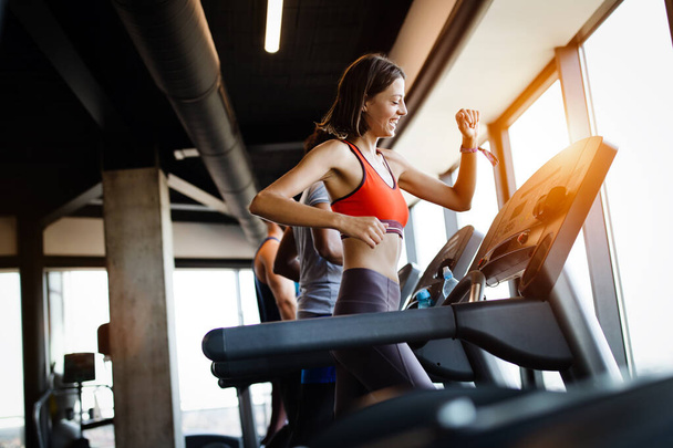 Young fit people running on a treadmill in health club. - Фото, зображення