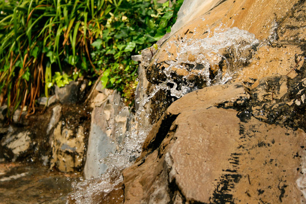 Víz patak egy szökőkút fröccsenő víz cseppek sziklák háttér növényzet - Fotó, kép