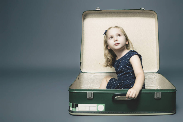 blond meisje zitten in een vintage koffer.  - Foto, afbeelding