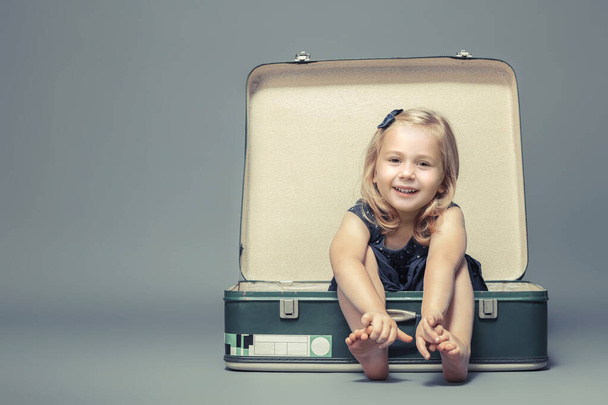 blond girl sitting in a vintage suitcase.  - Zdjęcie, obraz