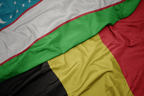 hadonászó színes zászló Belgium és nemzeti zászló Üzbegisztán. - Fotó, kép