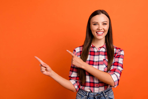 Portrait of her she nice attractive lovely cheerful glad content straight-haired girl pointing two forefingers aside ad advert new isolated on bright vivid shine vibrant orange color background - Foto, immagini