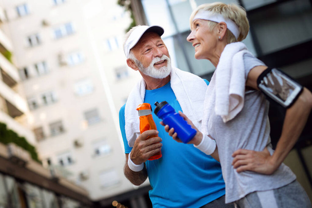 Senior couple drinks water to replenish energy and to hydrate - Фото, изображение