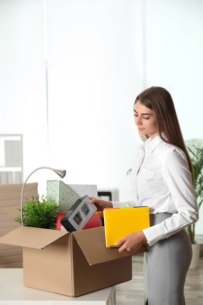 Szczęśliwa młoda kobieta pakuje rzeczy do pudełka w biurze - Zdjęcie, obraz