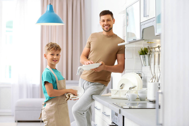 Dad and son wiping dishes in kitchen - Valokuva, kuva
