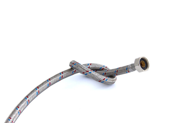 Vstupní hadice vodovodního kohoutku kovová prýmka, uvázaná v uzlu izolovaném na bílém - Fotografie, Obrázek