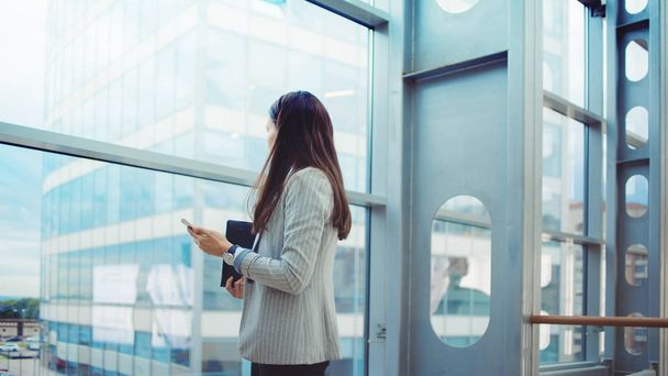 Young businesswoman with glasses and a phone in her hands. In the office or business center. - 写真・画像