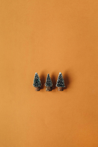 Tree toy Christmas fir-trees on ginger background. Flat lay, top view Christmas / New Year minimal concept. - Фото, изображение