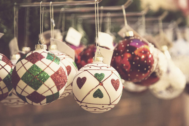 Christmas glass balls decorated with glitter hanging on a shelf of a decoration shop - 写真・画像